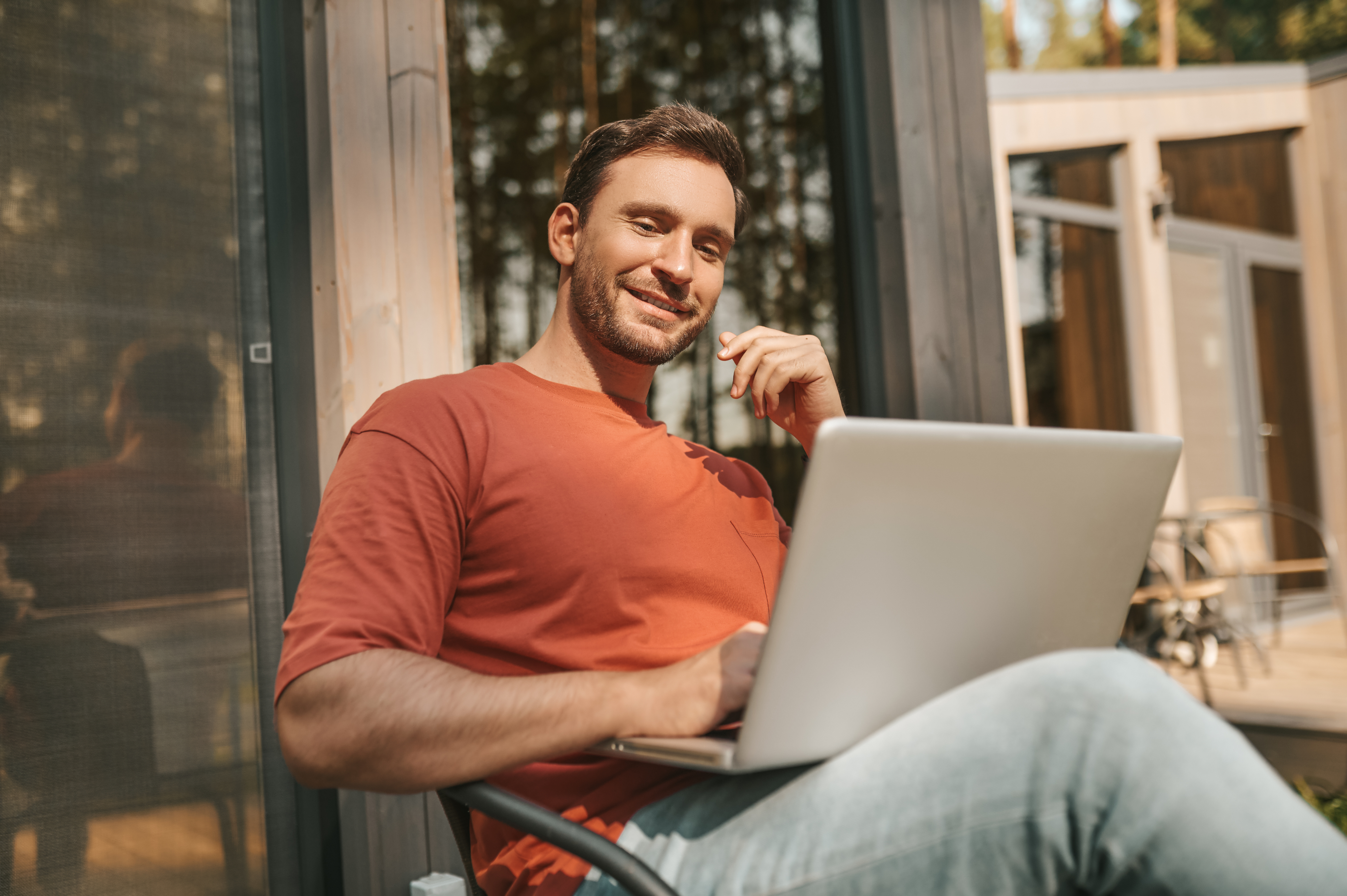 Smiling man working on a laptop outdoors